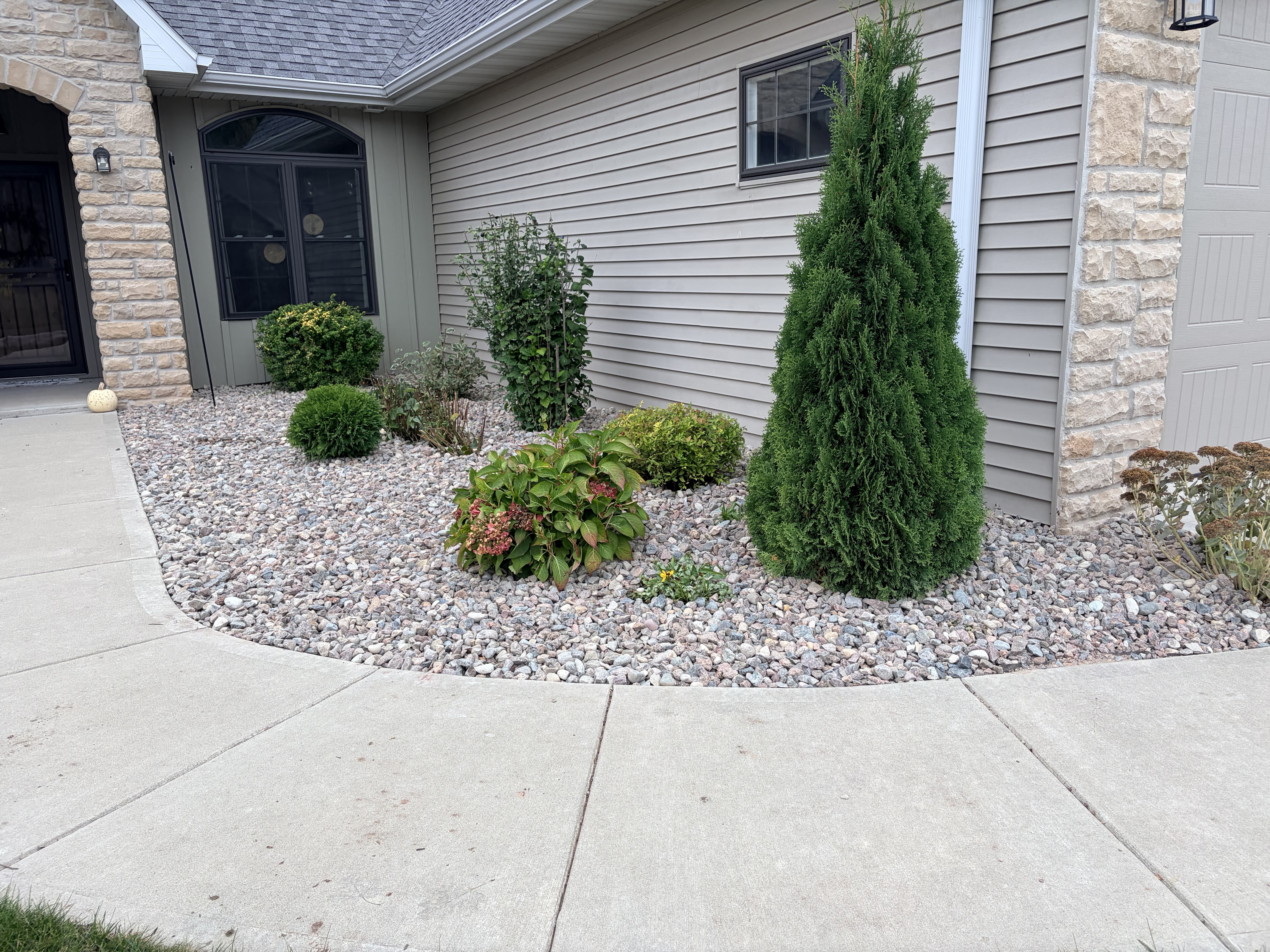 Fresh stone landscape bed with shrubs and evergreens along a home's entry